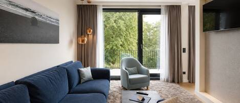 A modern living room with a sofa, armchair, and a flat-screen TV.