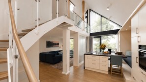 A modern interior with a staircase, a living area with a sofa, a kitchen with a dining area, and large windows. - Maremüritz Yachthafen Resort (Waren (Müritz))