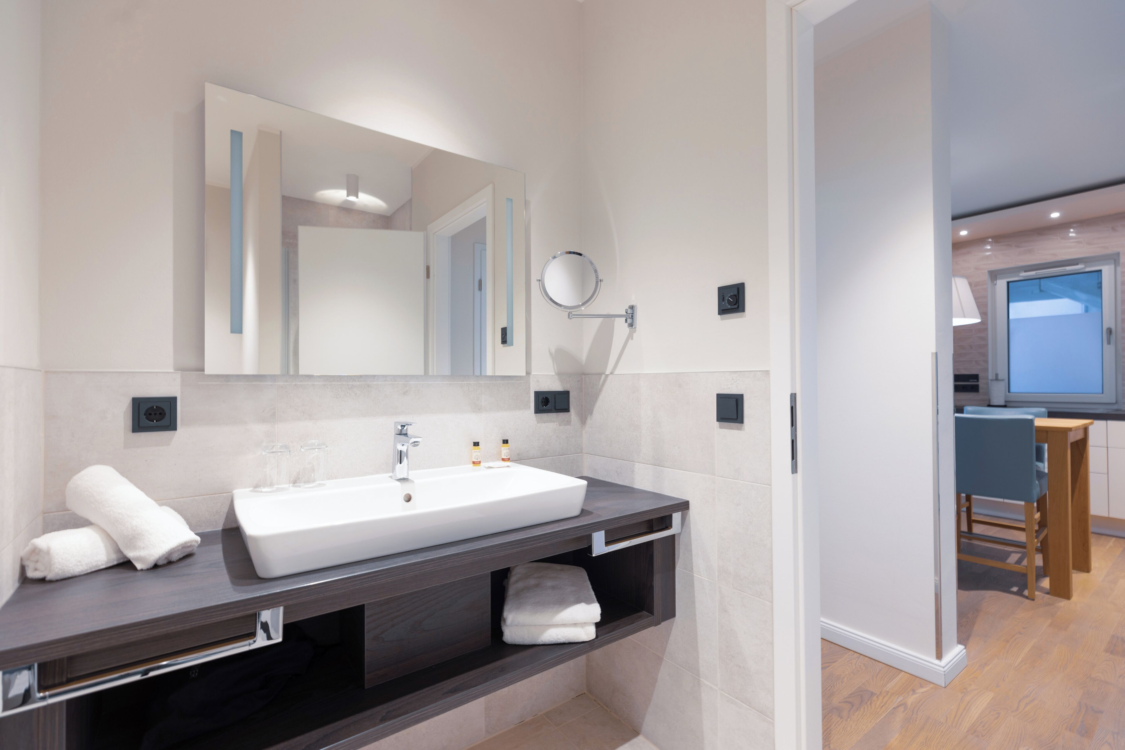 A modern bathroom with a large sink, mirror, and built-in shelves.