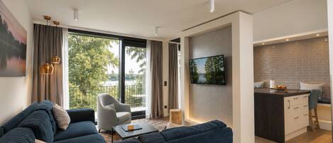 Un salon moderne avec un canapé, un fauteuil et un téléviseur fixé au mur.