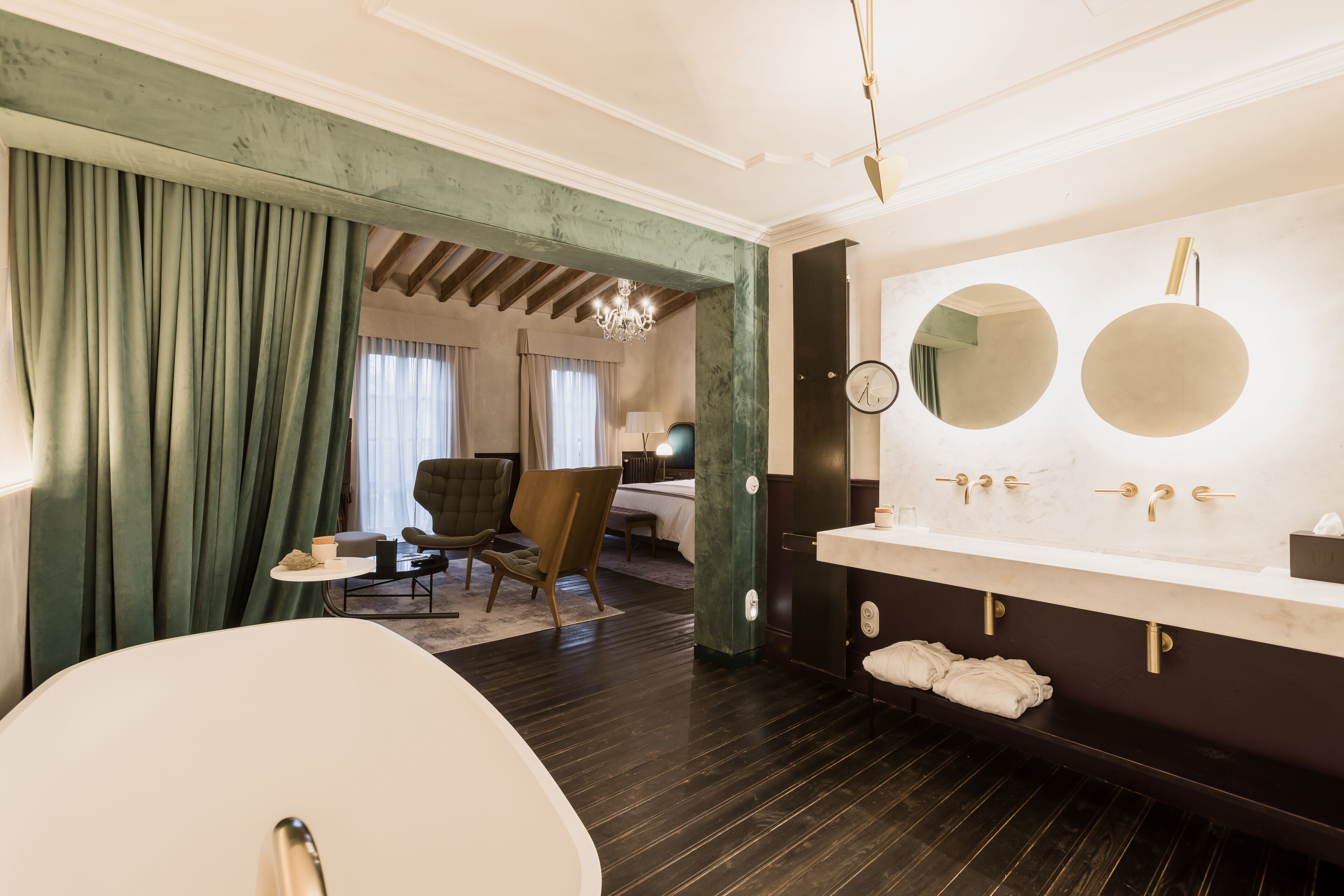 A modern bathroom with a large bathtub, a double vanity with two sinks, and a mirror above the vanity.