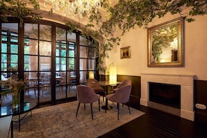 A room with a fireplace, a table with chairs, and a large window with a view of the outdoors. - Can Bordoy Grand House Hotel GL Preferred Hotel (Palma de Mallorca)