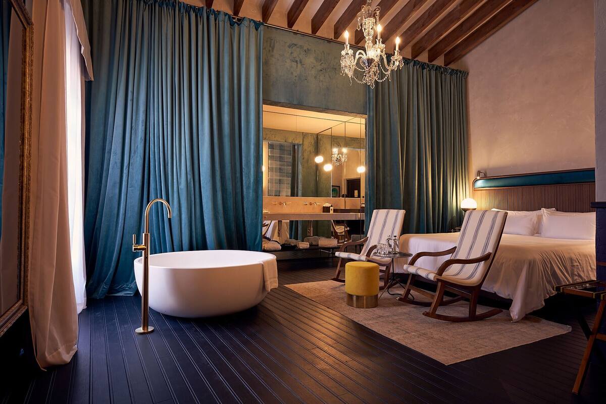 Une salle de bain moderne avec une baignoire sur pieds, un grand miroir et un lustre.
