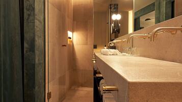 A modern bathroom with a glass shower enclosure, a vanity with a large mirror, and multiple sinks.