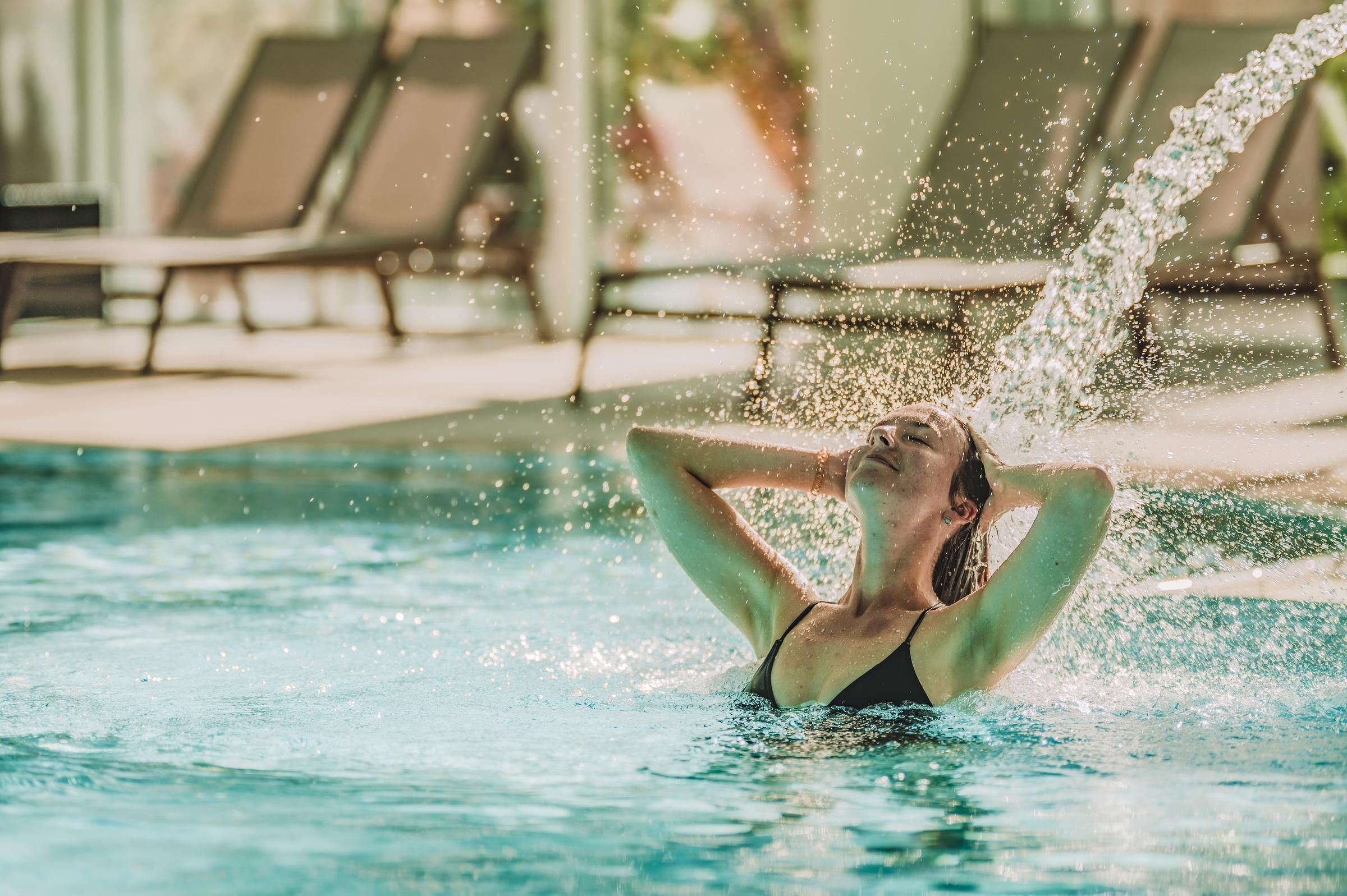 A person in a swimming pool with water splashing around them.