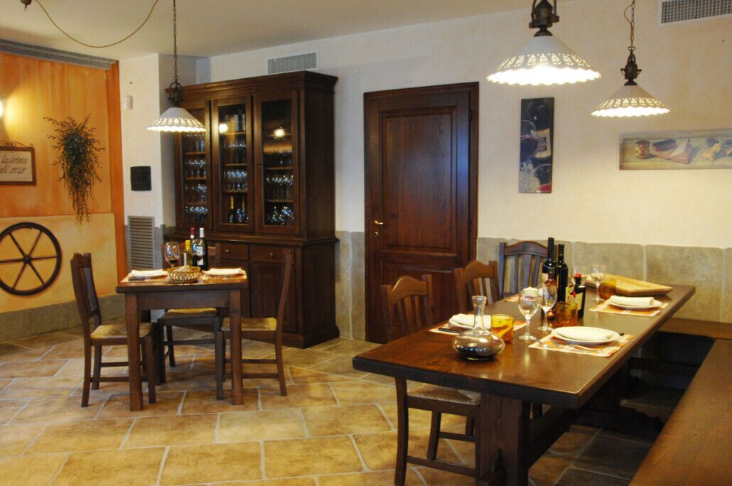A dining area with a wooden table set for two, a cabinet with glassware, and pendant lighting.