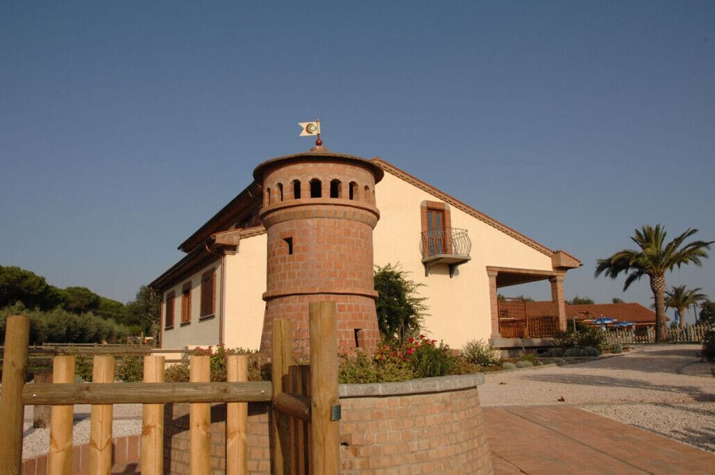 A building with a tower, a balcony, and a flag.