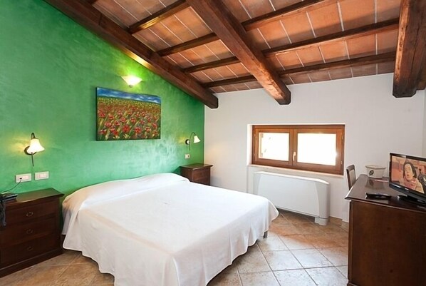 A bedroom with a bed, a painting, a window, and a radiator. - Agriturismo Corte in Fiore (Ardea)