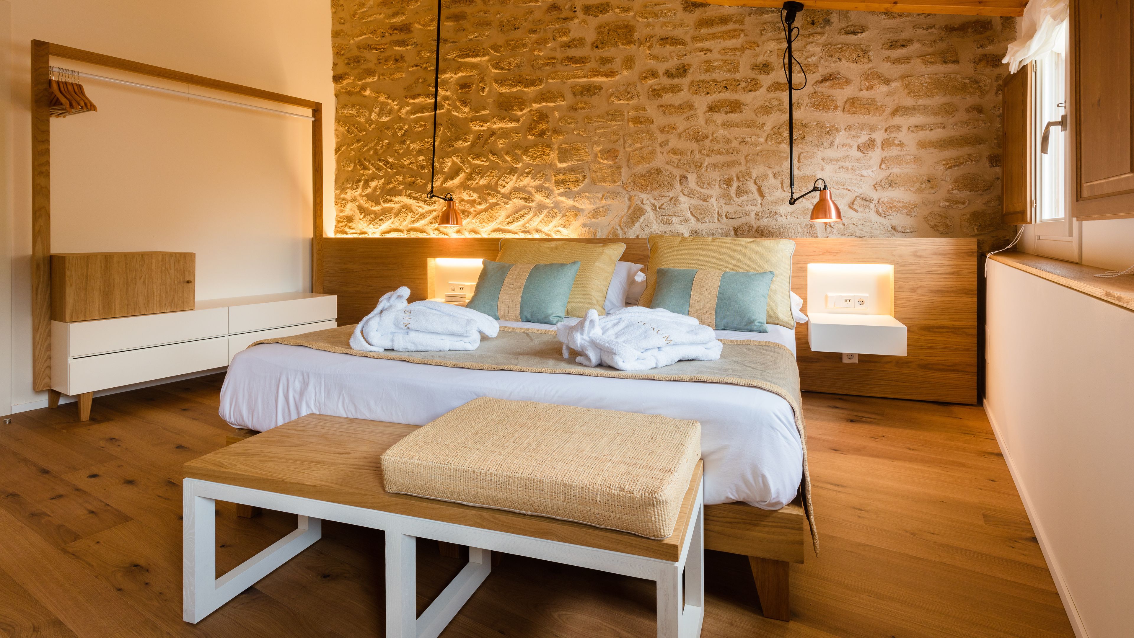 Ein modernes Schlafzimmer mit Steinwand, Holzmöbeln und zwei Nachttischlampen.