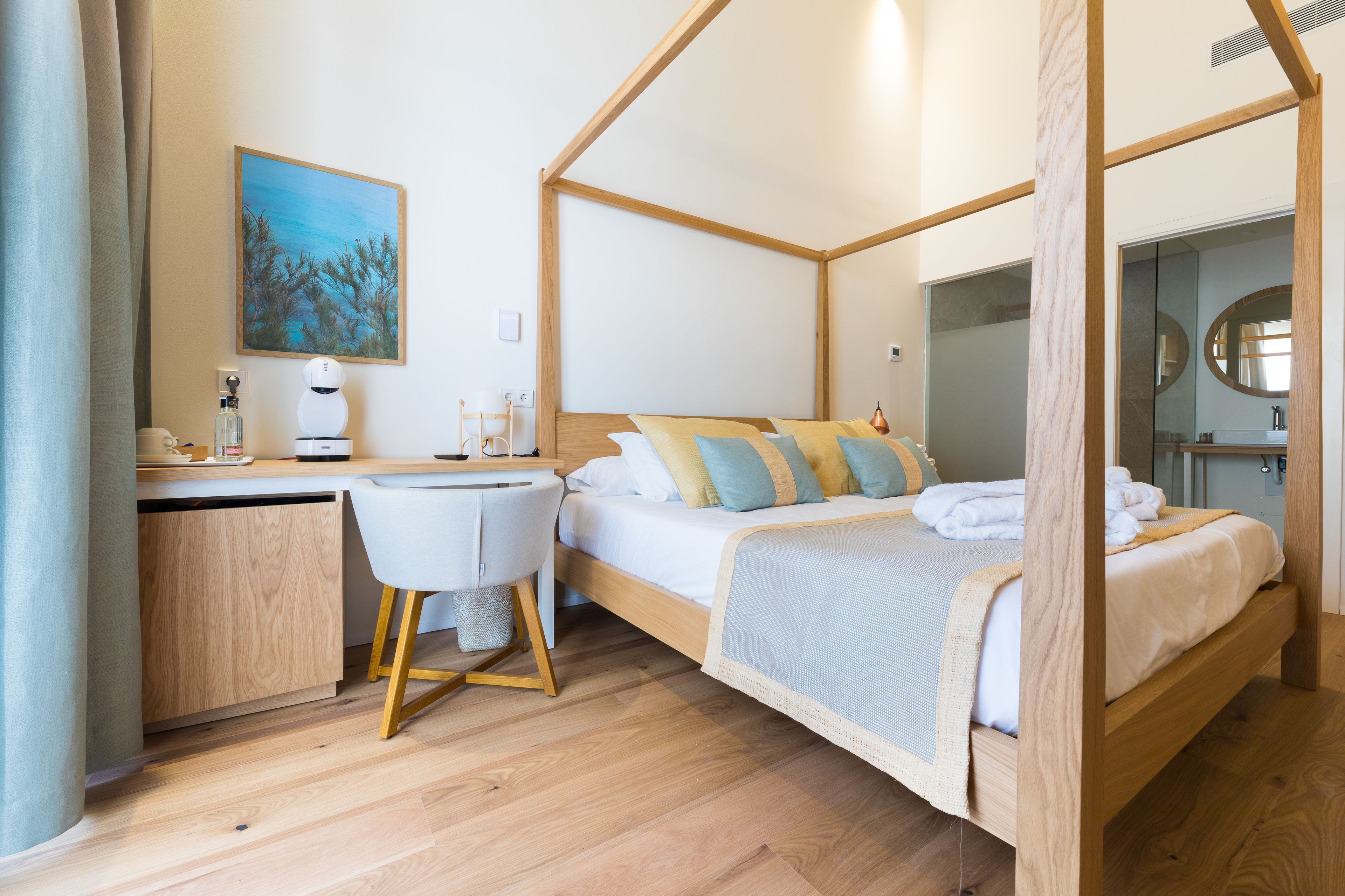 Ein Bett mit Baldachin aus Holz, ein Schreibtisch mit Stuhl und ein Bild an der Wand.