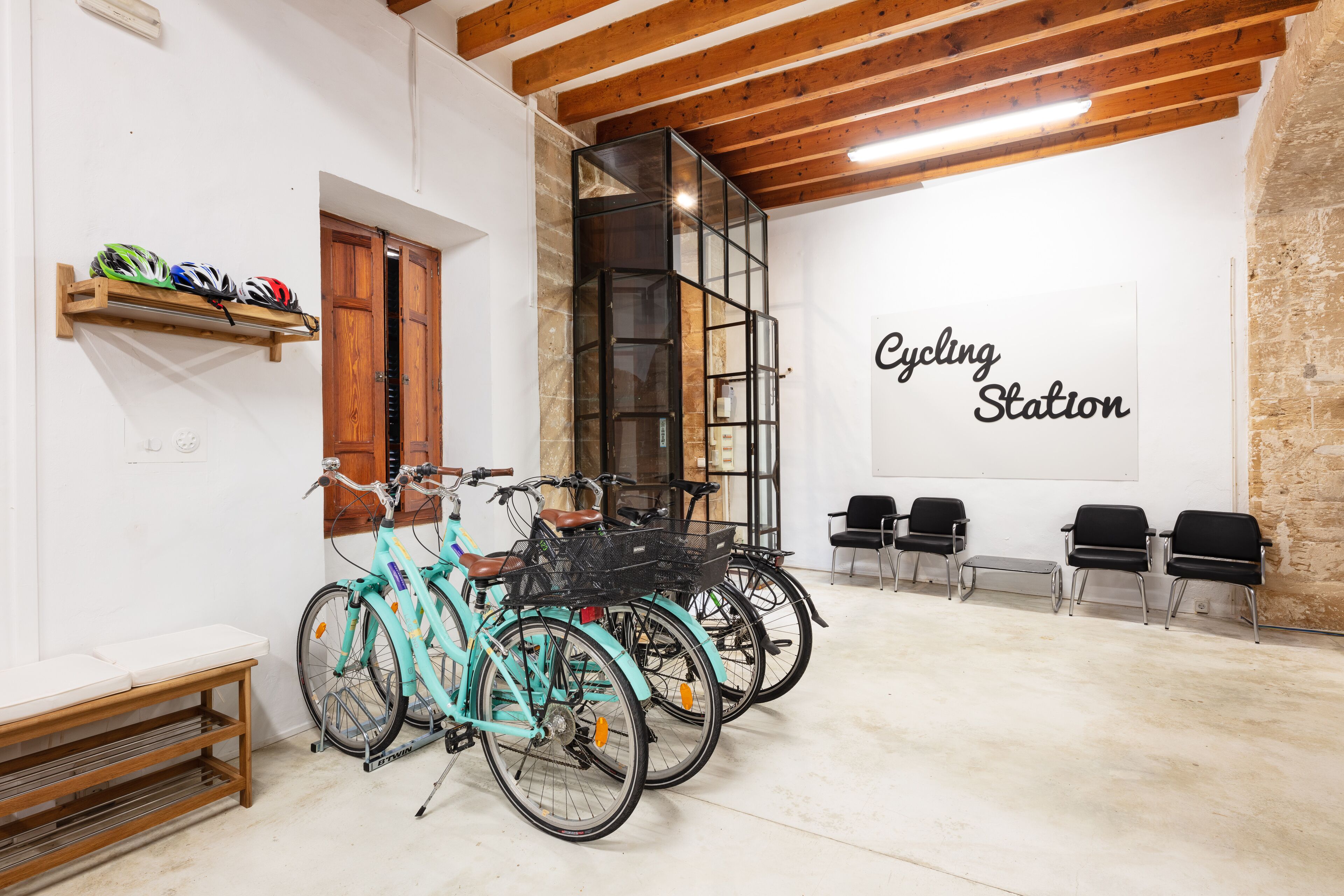 Una habitación con bicicletas, un banco de madera y una pared con el texto 'Cycling Station'.