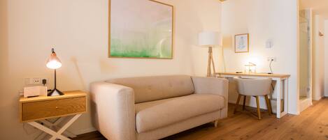 A cozy living room with a sofa, a desk, and a lamp.