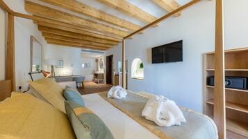 Une chambre d’hôtel moderne avec un plafond en bois, un grand lit recouvert d’une couette beige et verte, un téléviseur à écran plat et une étagère en bois.