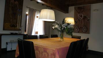Un comedor con una mesa de madera, sillas negras, un florero con flores y una obra de arte con una bicicleta colgada en la pared.