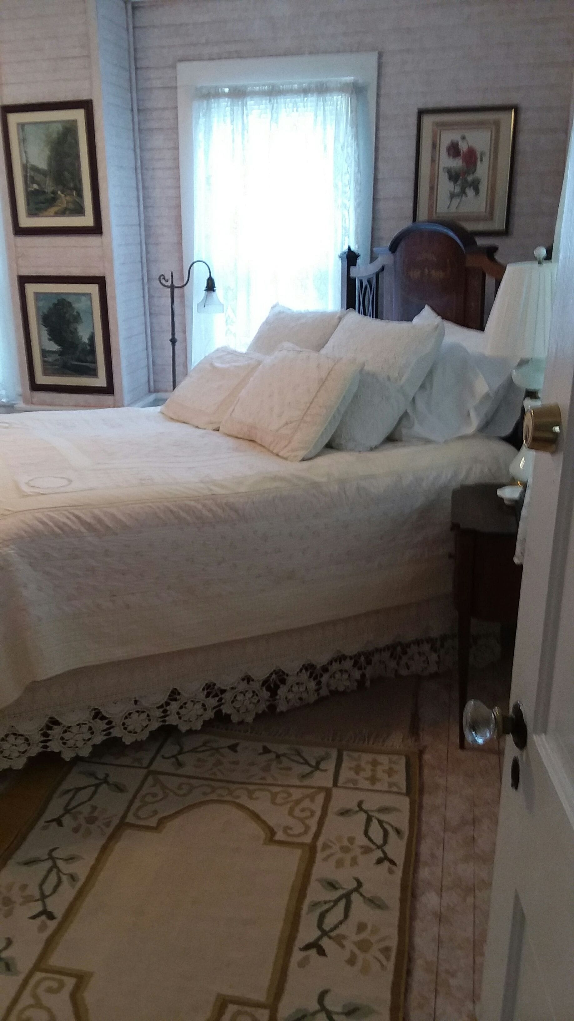 A bedroom with a bed, a nightstand, a lamp, and a door.