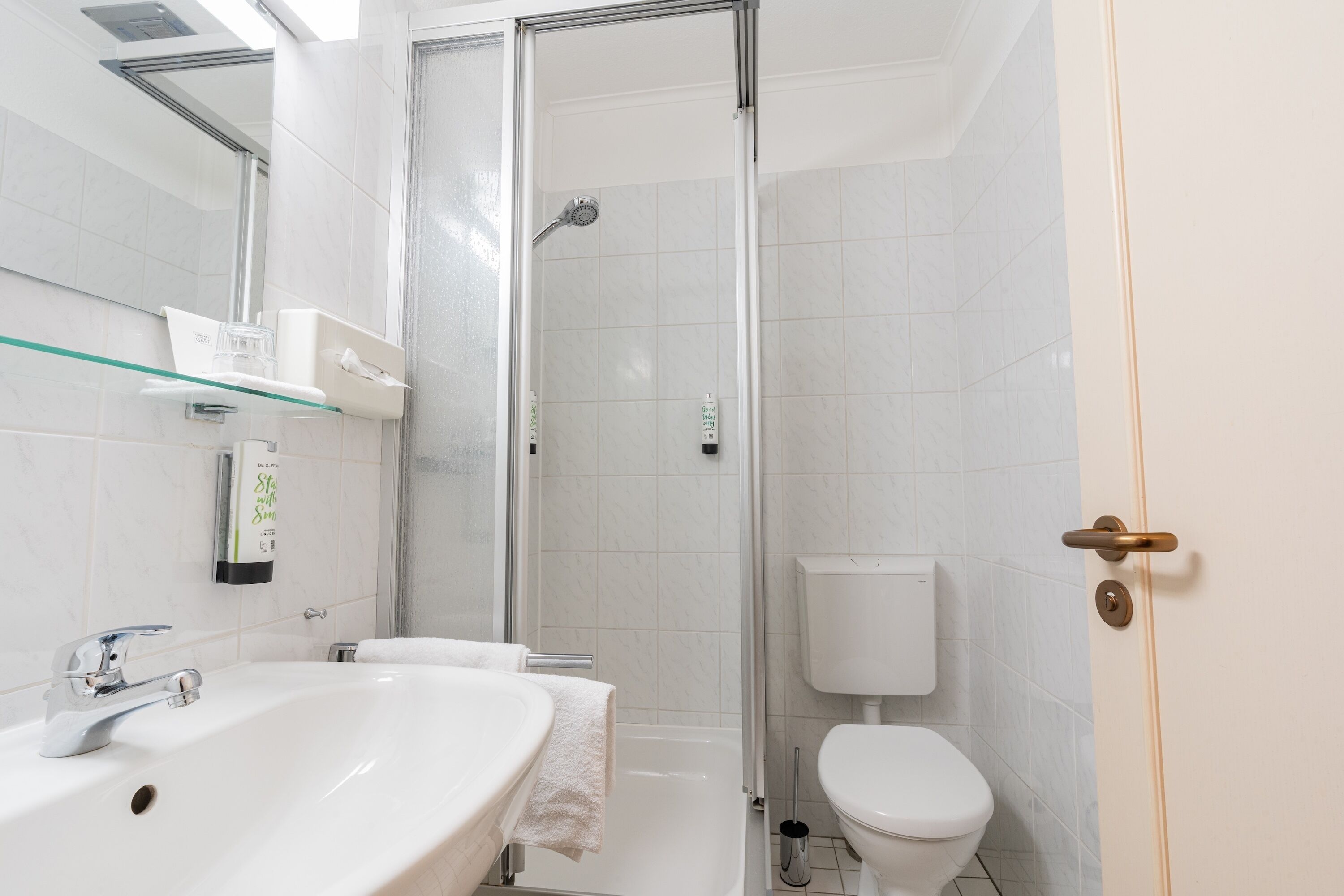 Un baño con cabina de ducha de vidrio, un lavabo blanco y un inodoro.
