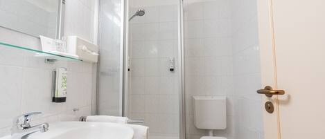 Un baño con cabina de ducha de vidrio, un lavabo blanco y un inodoro.