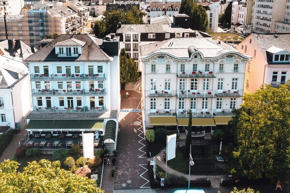 A multi-story hotel with balconies, a parking area, and a street view.