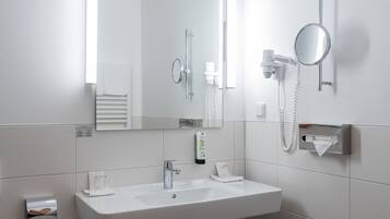 Ein modernes Badezimmer mit Waschbecken, Spiegel, Handtuchspender und einem Fön.