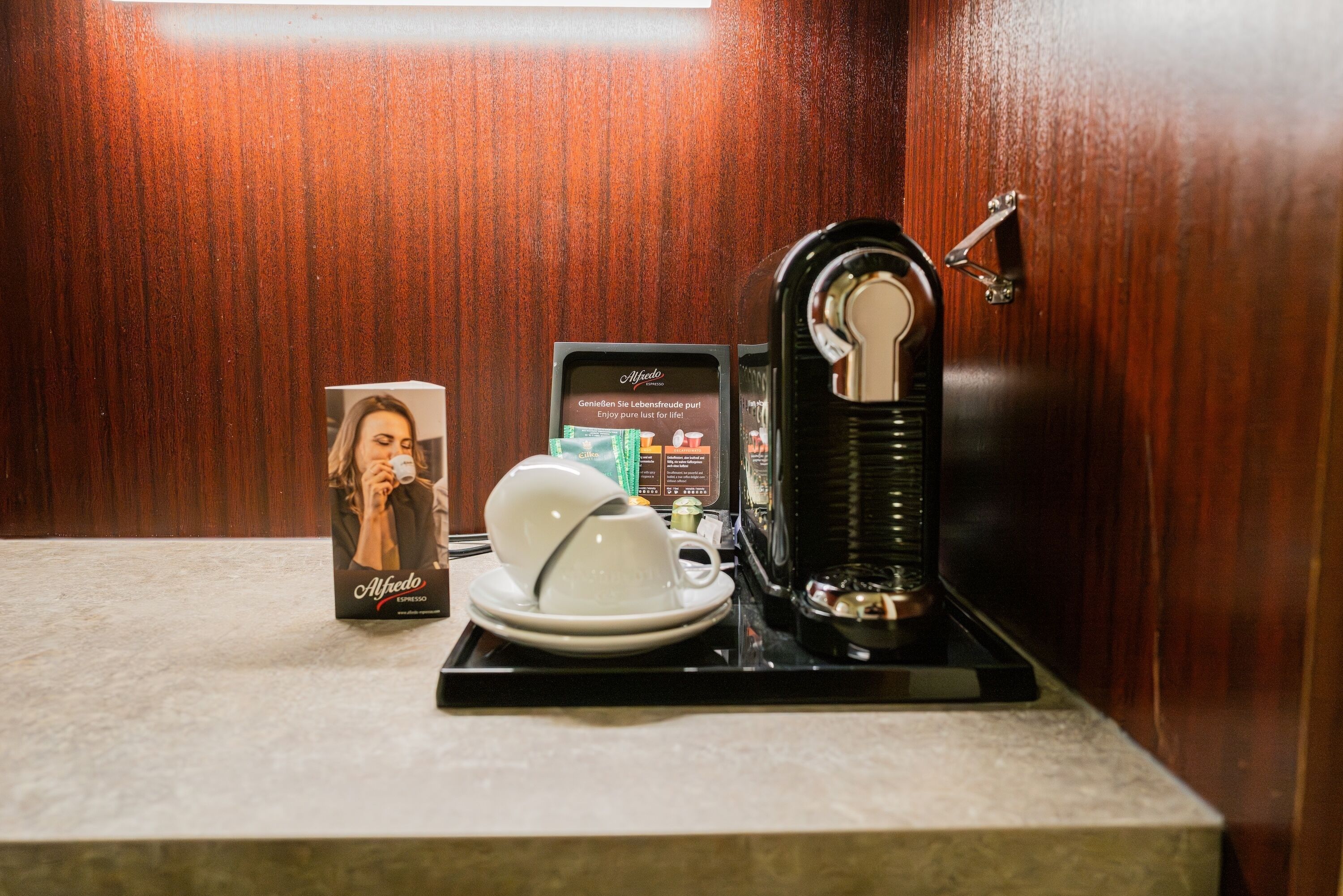 Eine Kaffeestation mit Kaffeemaschine, Tasse und Untertasse sowie einer Kaffeepackung.