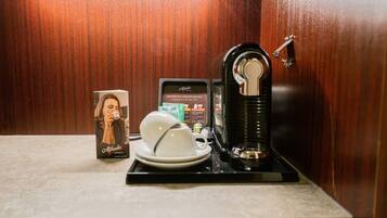 Eine Kaffeestation mit Kaffeemaschine, Tasse und Untertasse sowie einer Kaffeepackung.