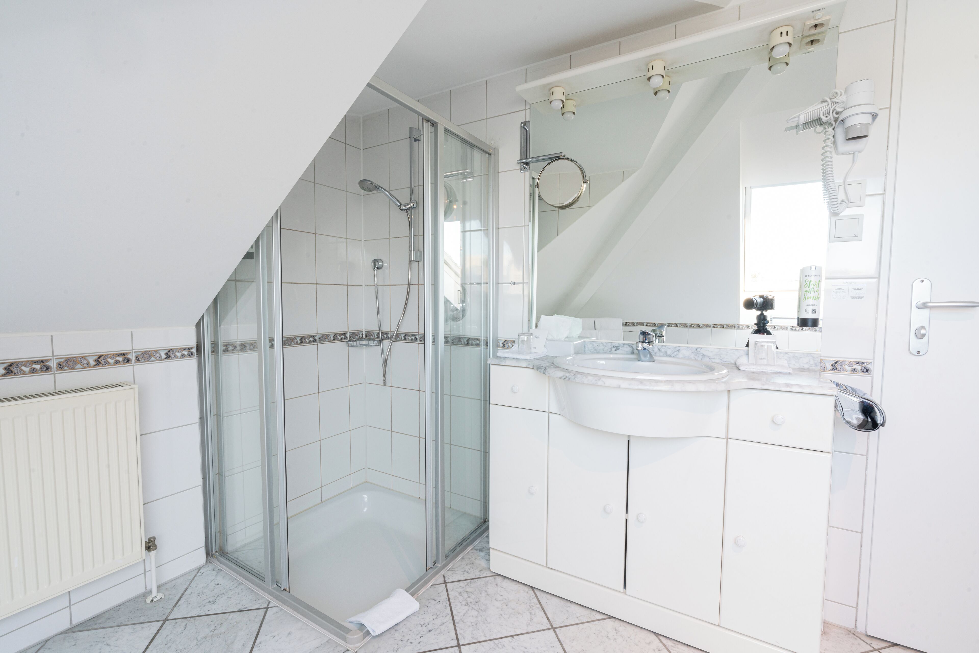 Une salle de bain moderne avec une douche à parois de verre, un meuble-lavabo à deux vasques et un grand miroir.