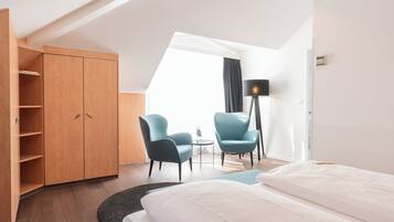 Ein Hotelzimmer mit einem Bett, zwei Stühlen, einem Schreibtisch, einem Kleiderschrank und einer Stehlampe.
