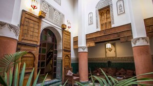 An interior with a wooden door, a wooden chair, a sofa, and a patterned floor. - Riad Hidaya (Fes)