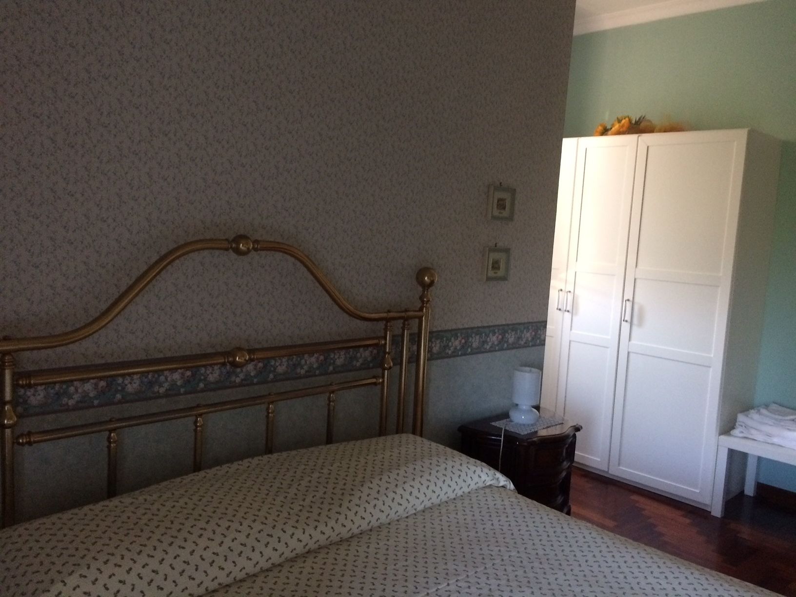 A bedroom with a bed, a wardrobe, and a nightstand.