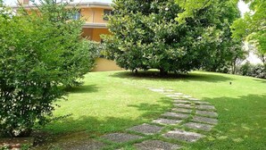 A well-maintained garden with a stone pathway leading to a central area surrounded by lush greenery and trees. - B&B a Casa Tua (Piedimonte San Germano)