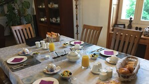 A dining table set with breakfast items, including croissants, fruit, and a loaf of bread. - La Musardine en Vexin (Omerville)