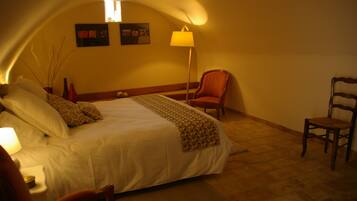 Una habitación de hotel con una cama grande, una silla, una lámpara y una mesita.
