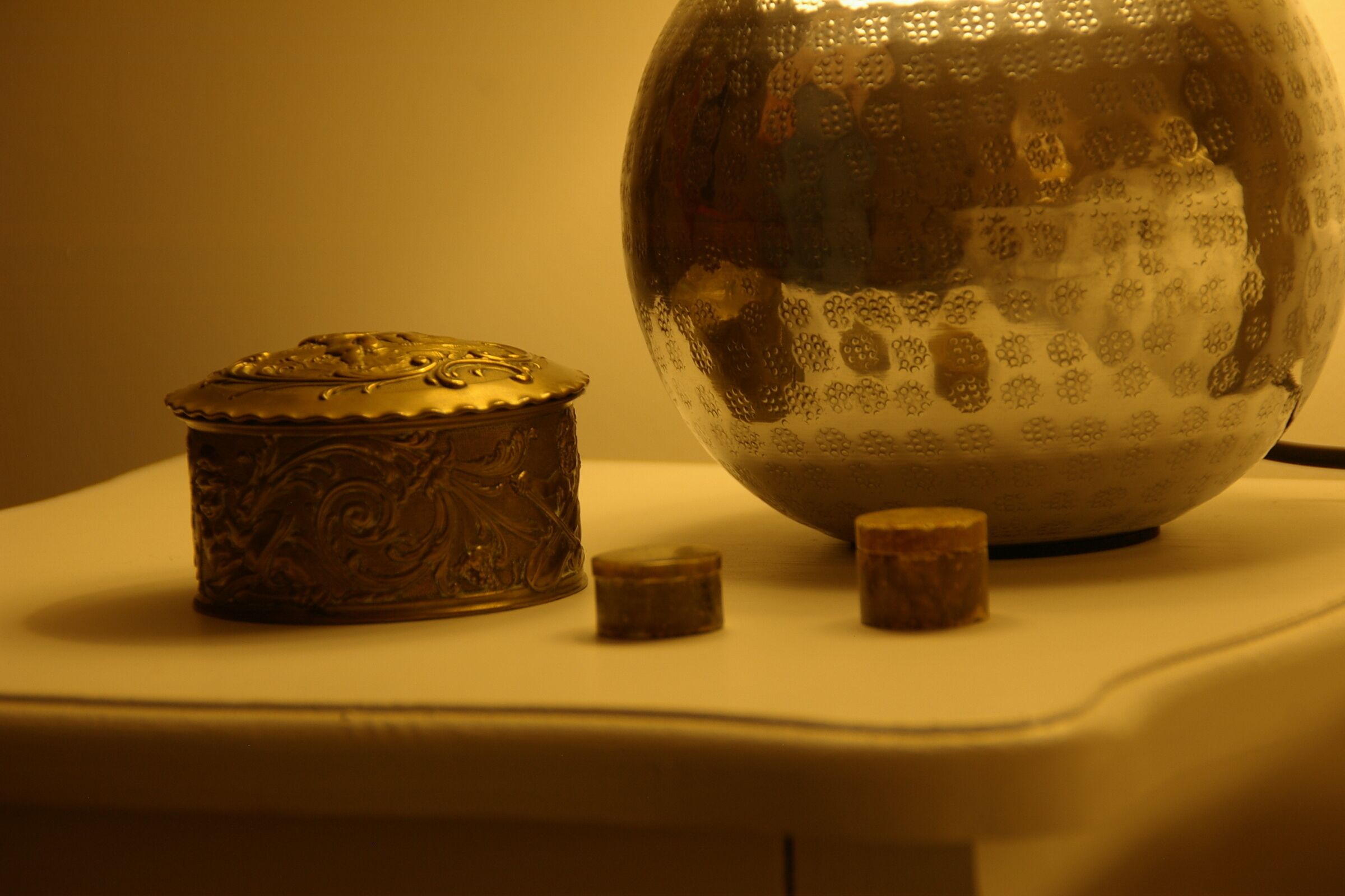 A decorative metal box and a reflective spherical object on a flat surface.
