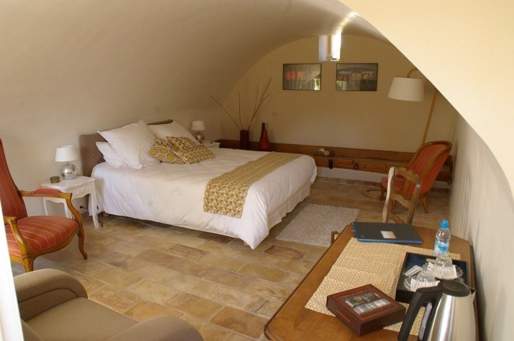 Ein Schlafzimmer mit einem Bett, Nachttischen, einem Sessel, einem Schreibtisch und einer Lampe.