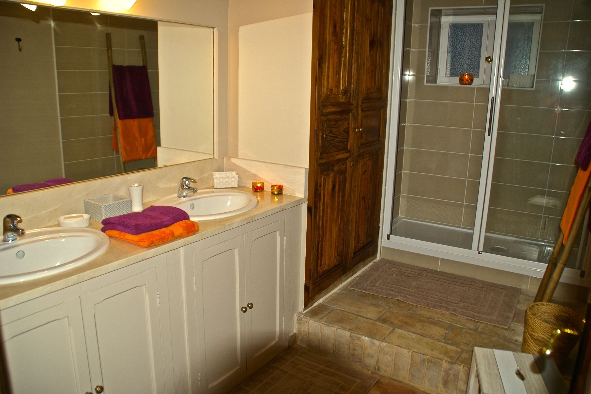 Ein Badezimmer mit zwei Waschbecken, einem Spiegel und einer Duschkabine.