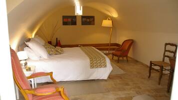 Une chambre avec un grand lit, un bureau et deux chaises.