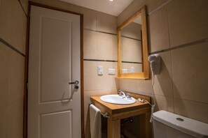 Une salle de bain avec un meuble-lavabo en bois, un lavabo blanc, un miroir et des toilettes.