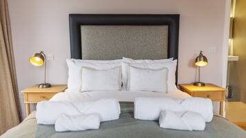 A neatly made bed with white linens and two bedside lamps.