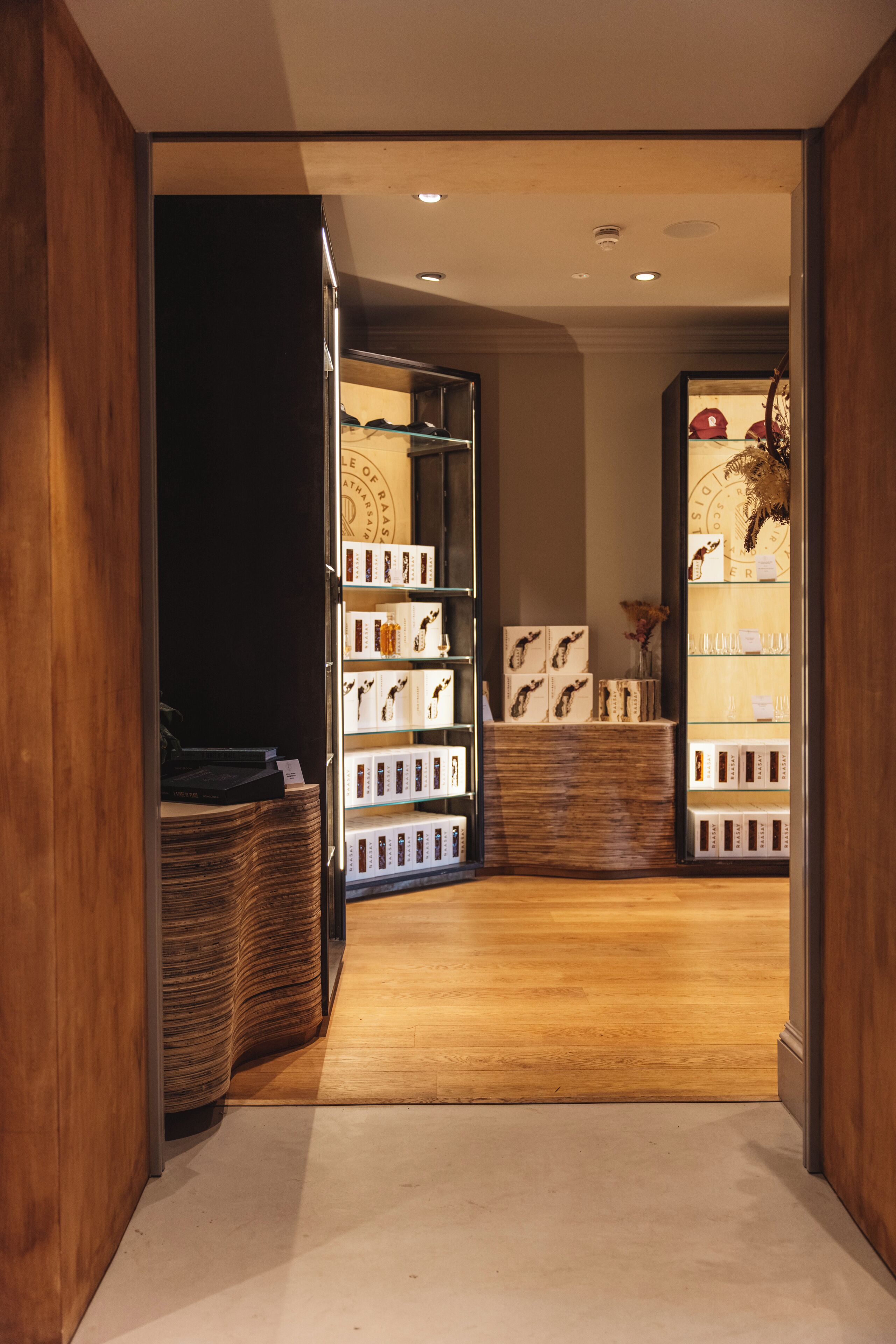 A modern hotel lobby with wooden flooring, a reception desk, and a display of framed photographs.