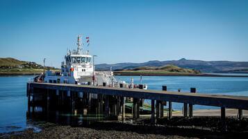 Un ferry atracado en un muelle, con vista despejada al agua y colinas distantes.