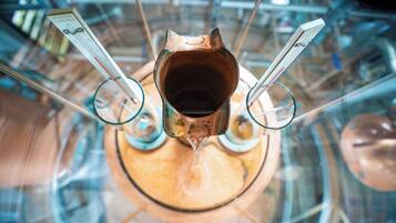 A top-down view of a copper kettle with a spout, surrounded by glassware.