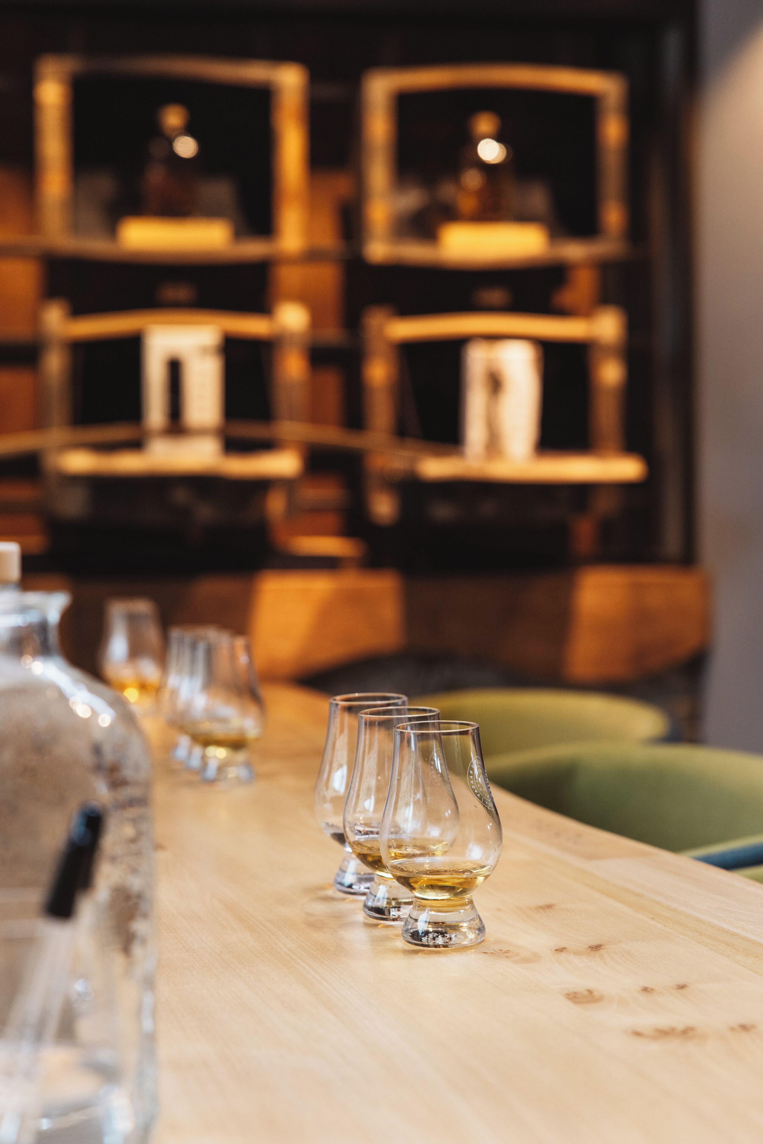 A bar area with a wooden counter, several glasses, and a bottle.