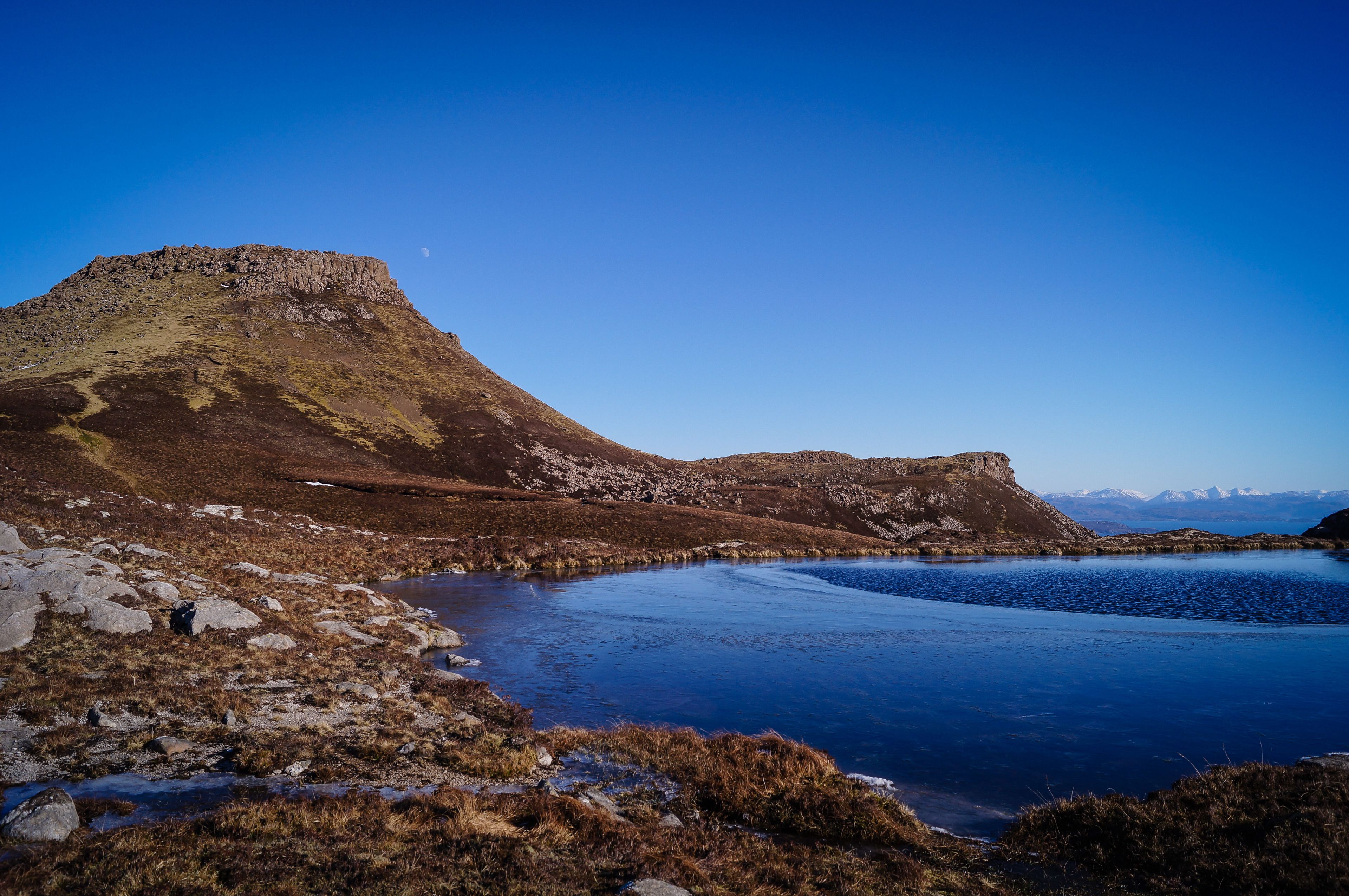 A mountainous landscape with a lake and a clear sky.
