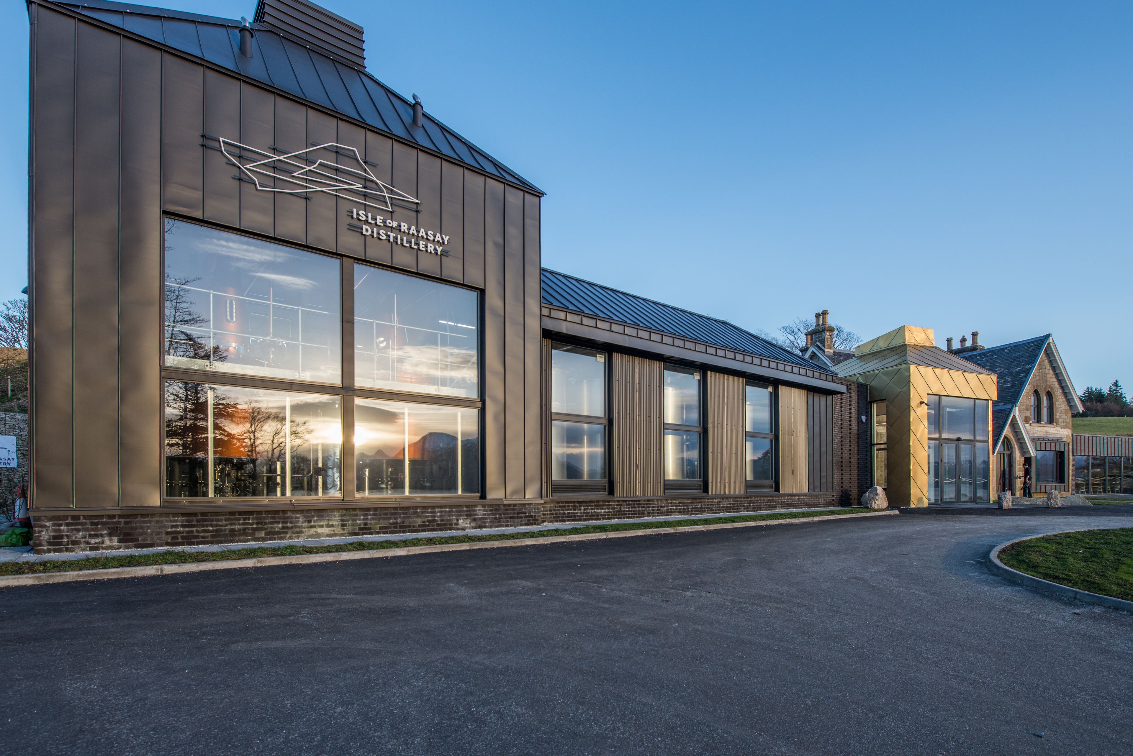 A modern building with large windows and a sign that reads "Isle of Raasay Distillery".