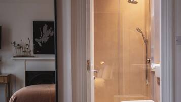 Une salle de bain moderne avec une douche à parois de verre, des toilettes blanches et un lavabo apparent.