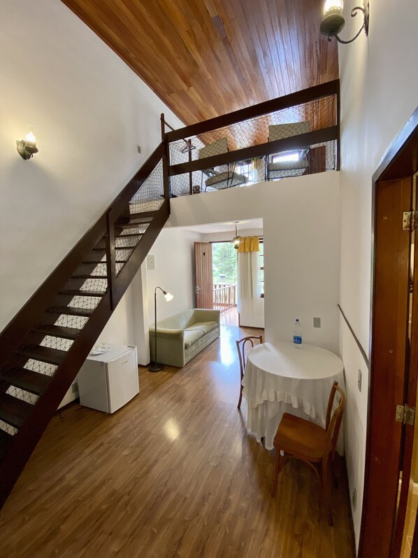 A spacious room with a wooden staircase, a dining area, and a view of the outdoors. - Hotel Fazenda São Moritz (Teresópolis)