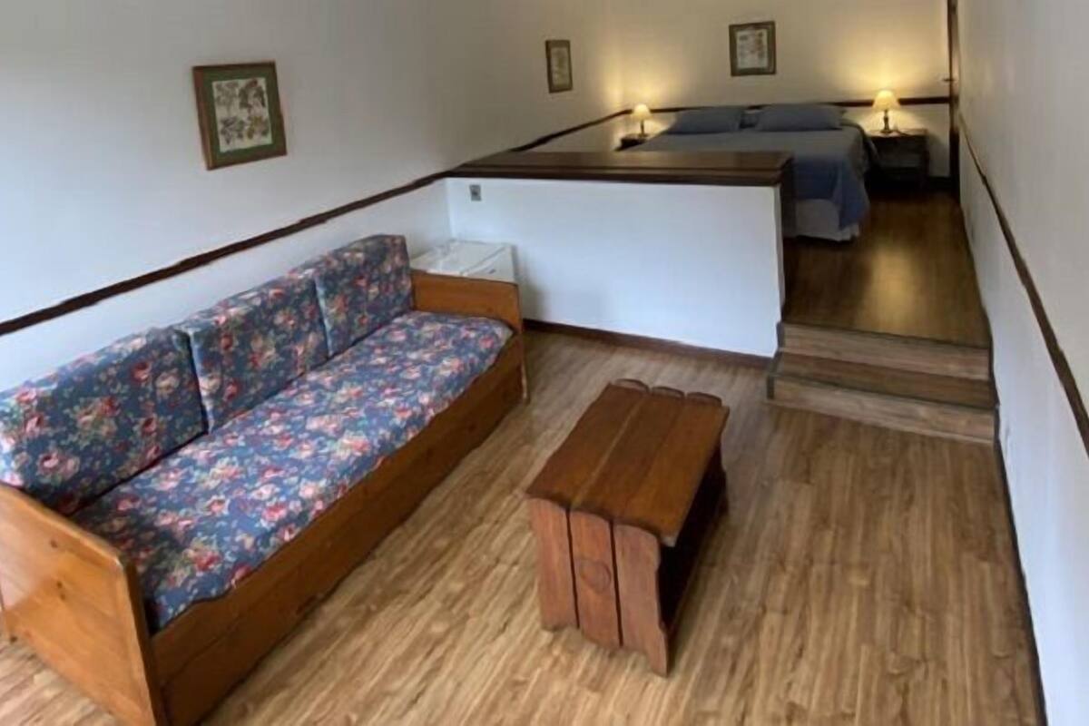Une pièce comprenant un canapé en bois, un banc et un lit avec une tête de lit.