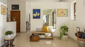 A hallway with a wooden bench, potted plants, and artwork on the walls. - Poseidon Residence (San Vito Lo Capo)