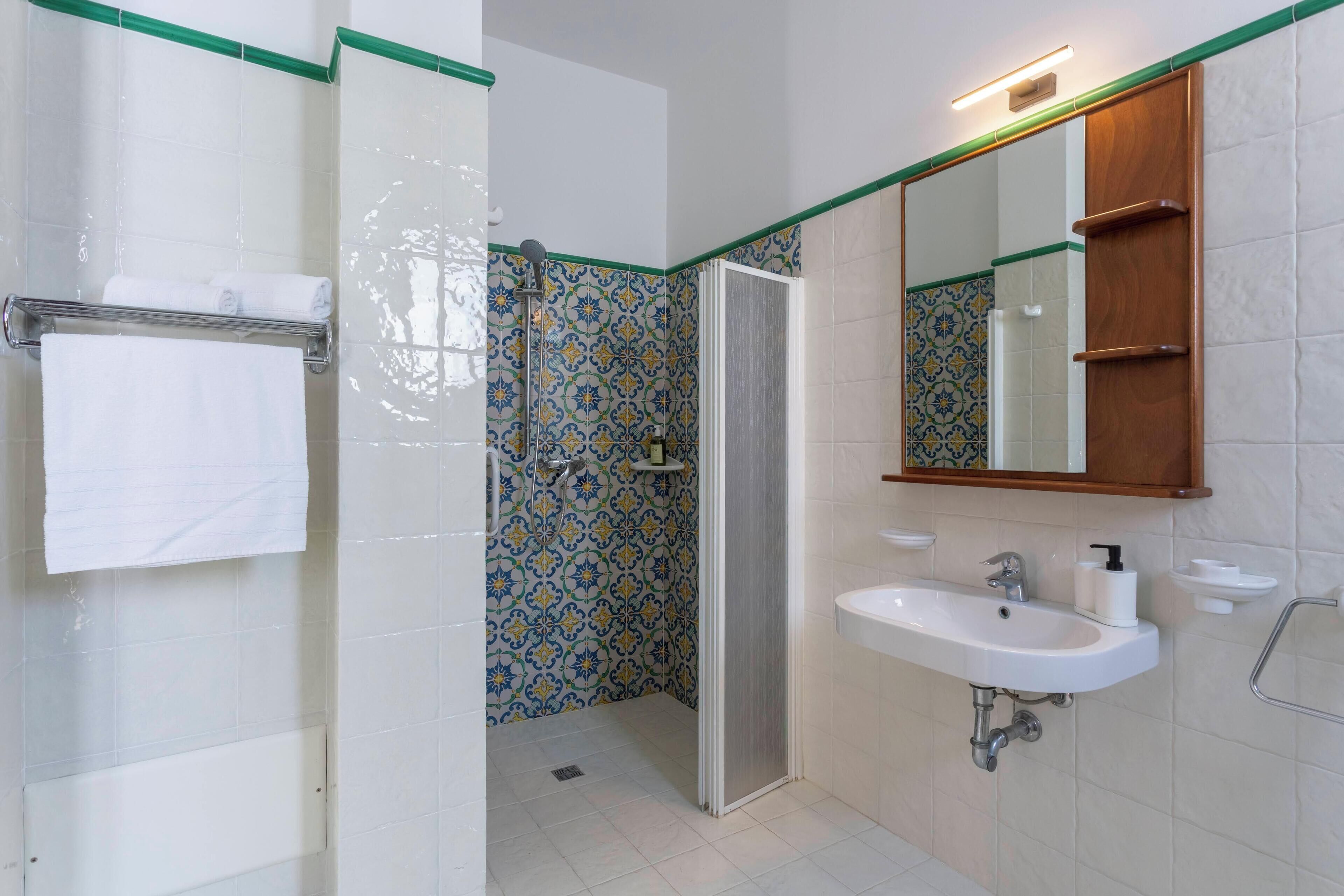 A bathroom with a shower, a sink, and a mirror.