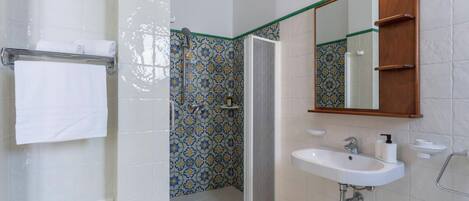 A bathroom with a shower, a sink, and a mirror.